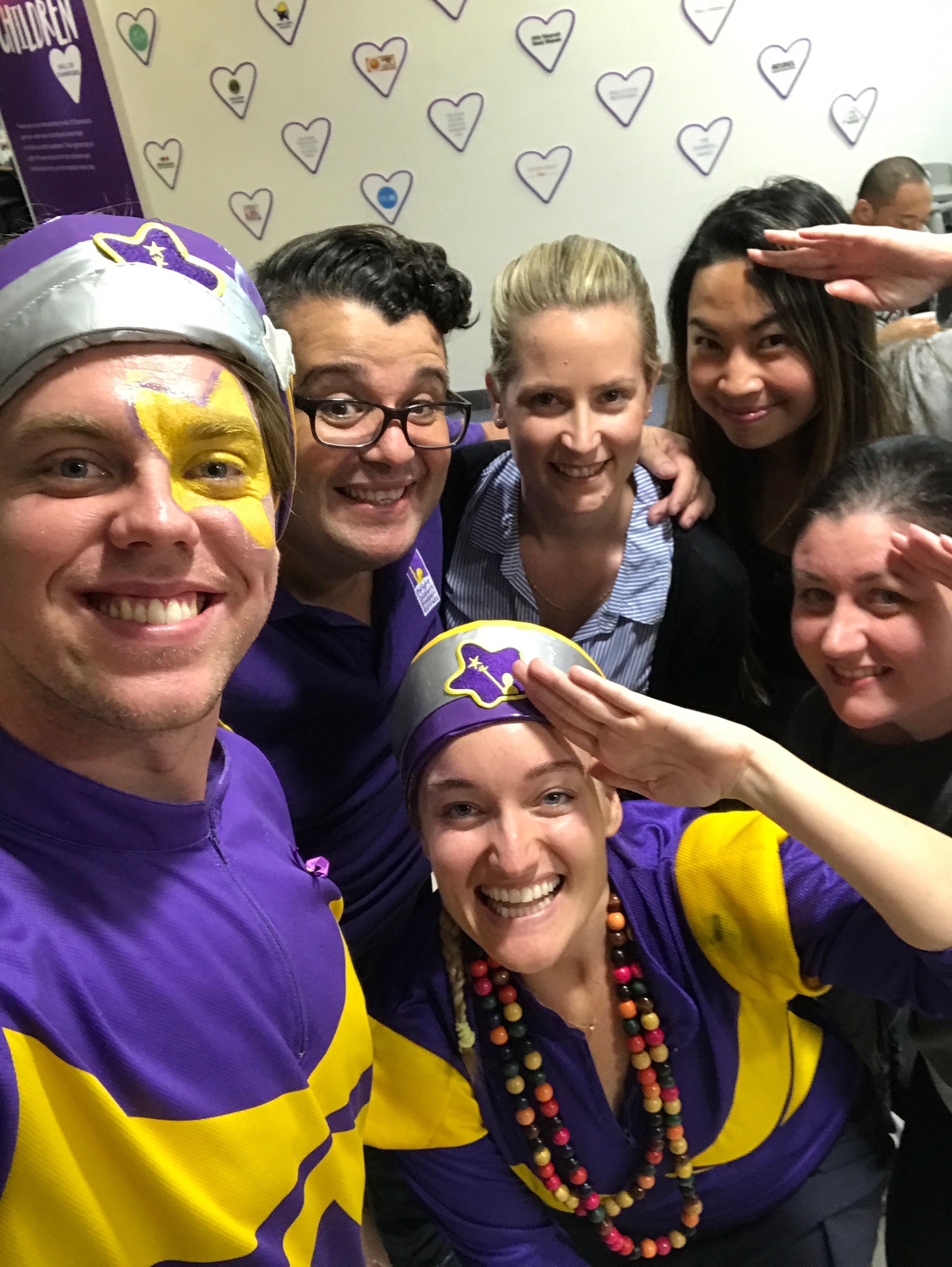 Group in purple and yellow superhero costumes at charity event